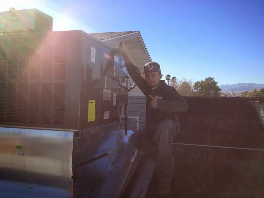 HVAC technician performing Heat Pump Repair on a rooftop unit in Branson